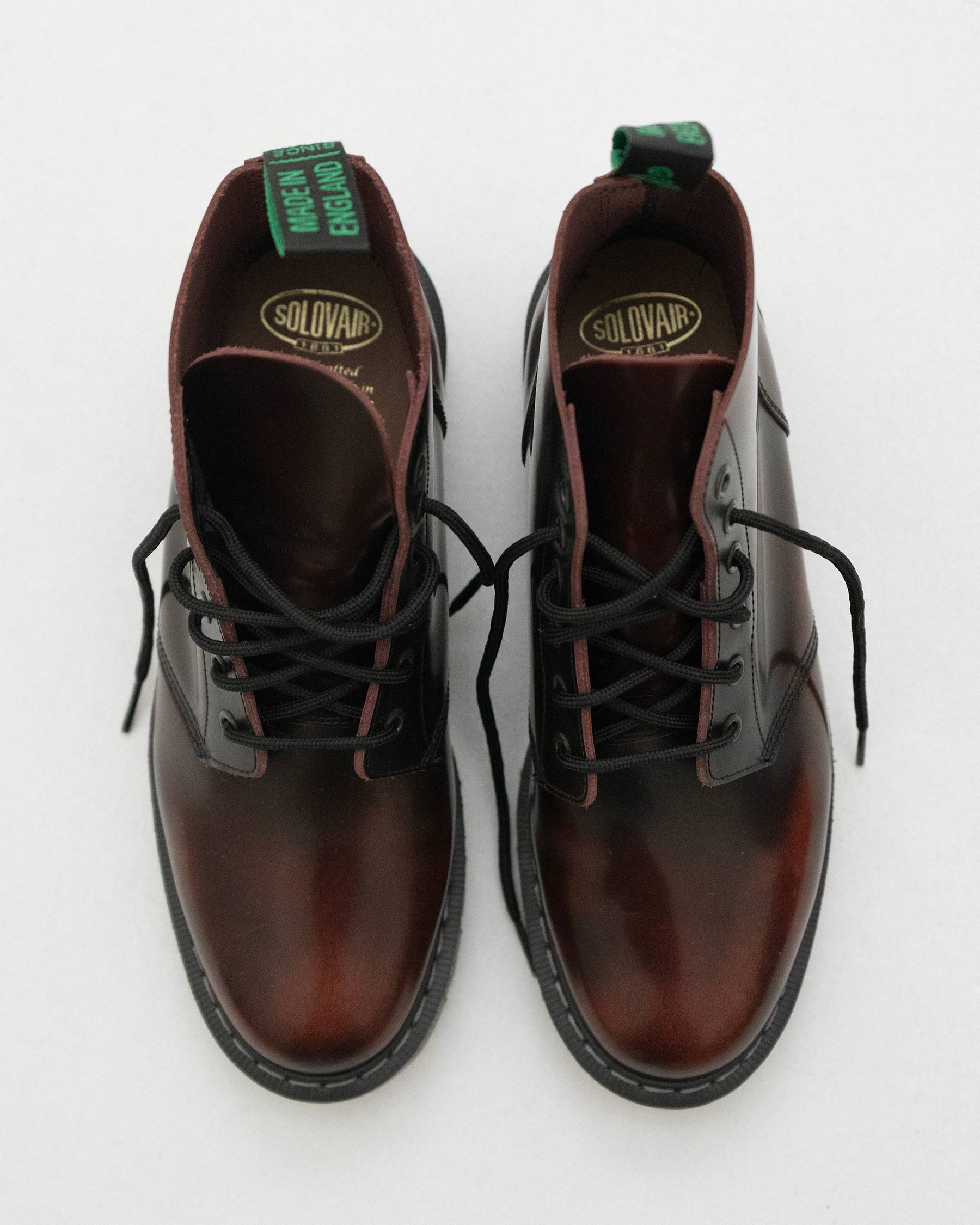 A pair of Solovair Burgundy Leather Astronaut Boots by Pyne and Smith Clothiers, with black laces, Goodyear welted soles, branded green and black heel pull tabs, and gold Solovair labels inside, shown from above on a light background.