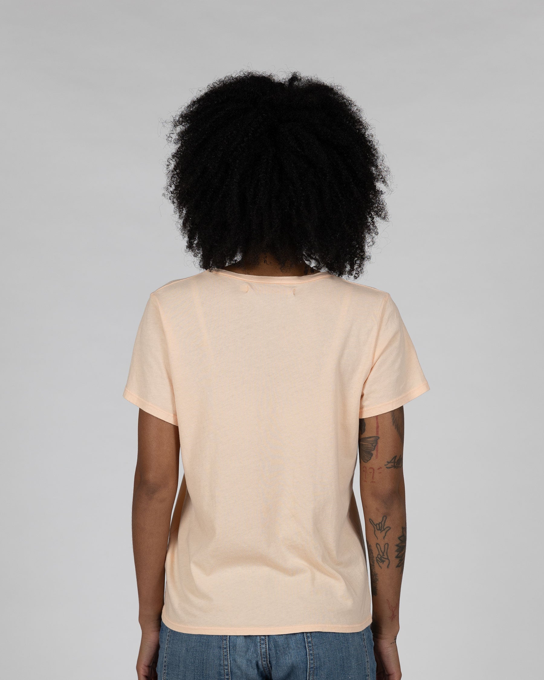 Back view of model wearing organic cotton apricot t shirt