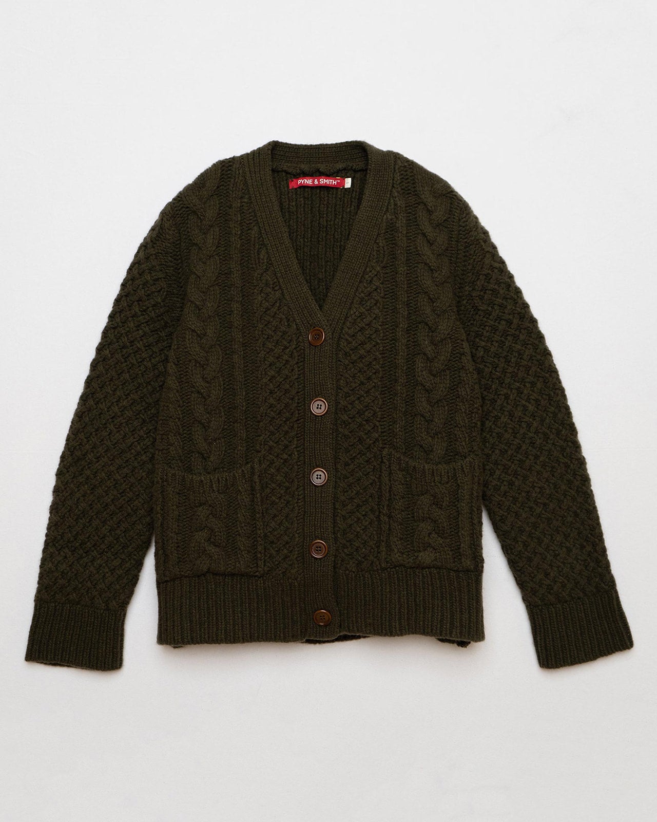 The Pyne and Smith Clothiers Merino Wool Cable Knit Cardigan with Pockets in Brunswick Green features a classic cable-knit pattern, front buttons, two pockets, and ribbed cuffs and hem, shown laid flat on a white background.