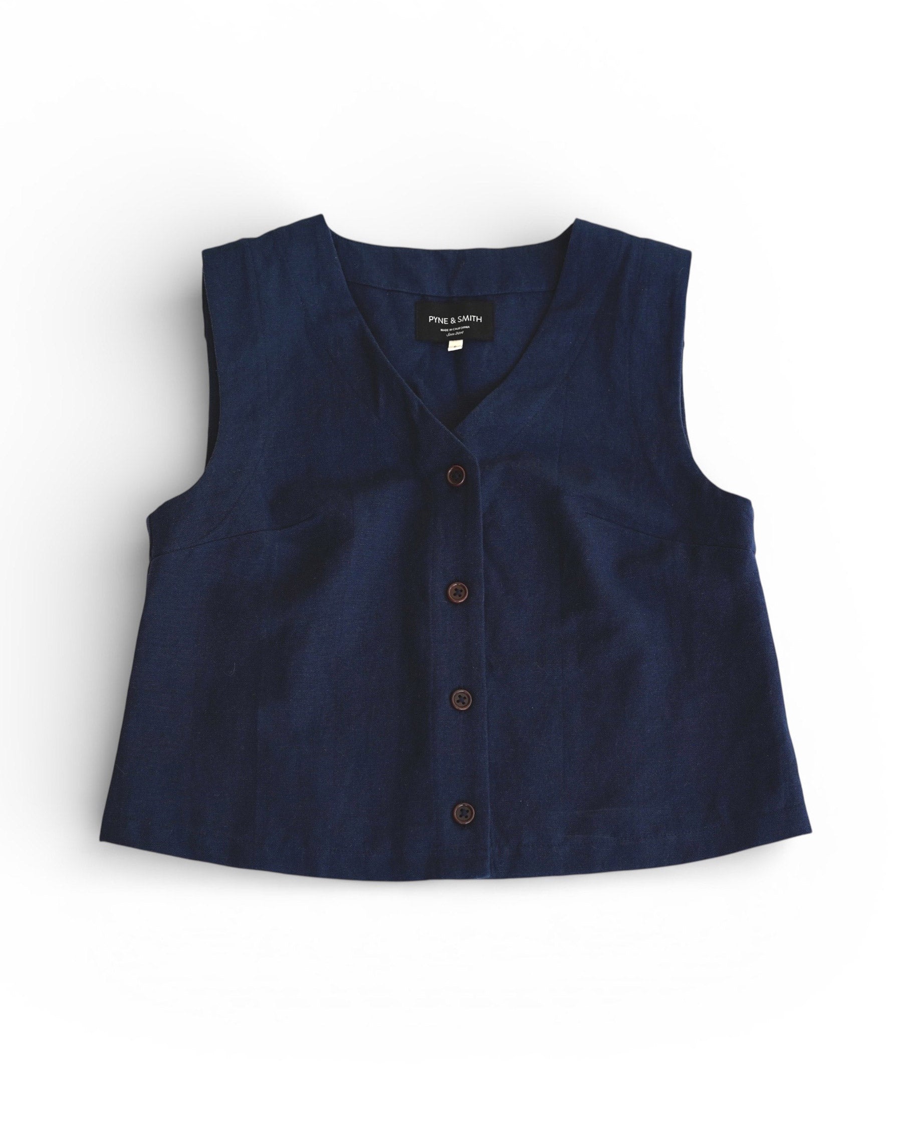 The Button up Vest in Ink Blue Canvas by Pyne and Smith Clothiers is a sleeveless, slim-fit vest with a V-neckline and button-up front, made from soft linen cotton, shown flat on a white background.