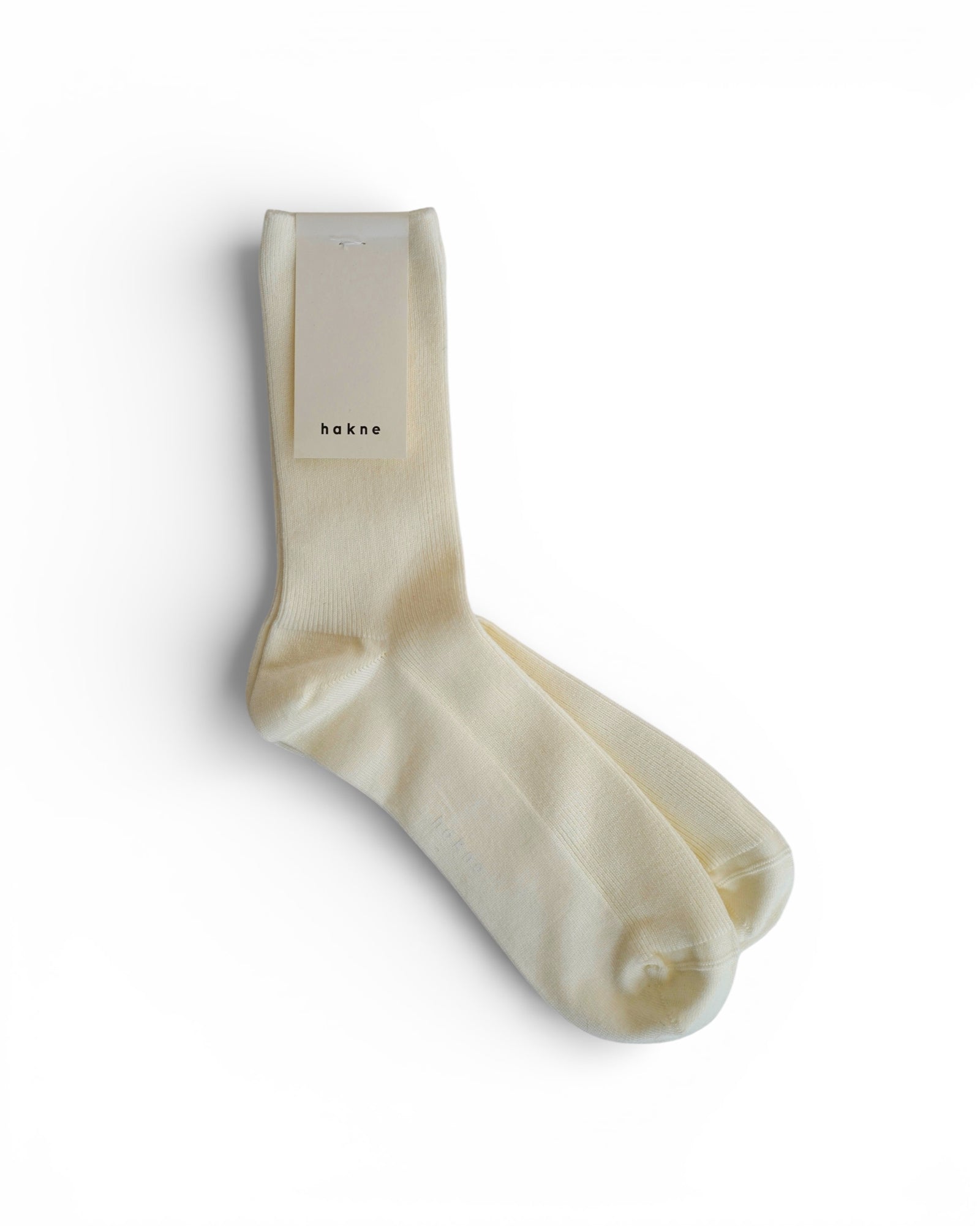 A pair of Merino Wool Ribbed Socks in cream by Pyne and Smith Clothiers, neatly stacked with a rectangular tag on top, displayed on a white background to highlight their refined quality.