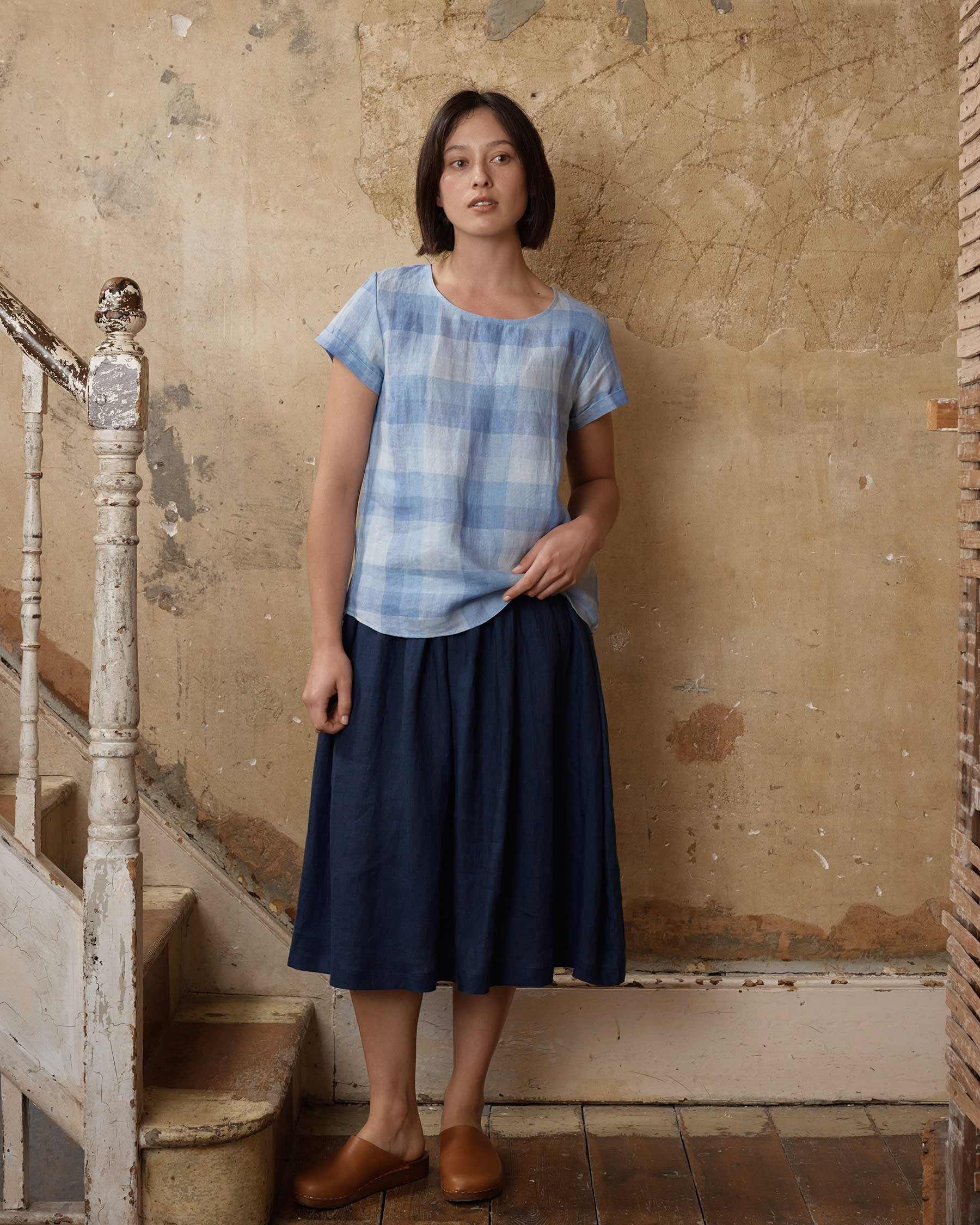 Model wearing linen t shirt blouse in blue Cala Stripe over Navy Blue linen skirt with pockets