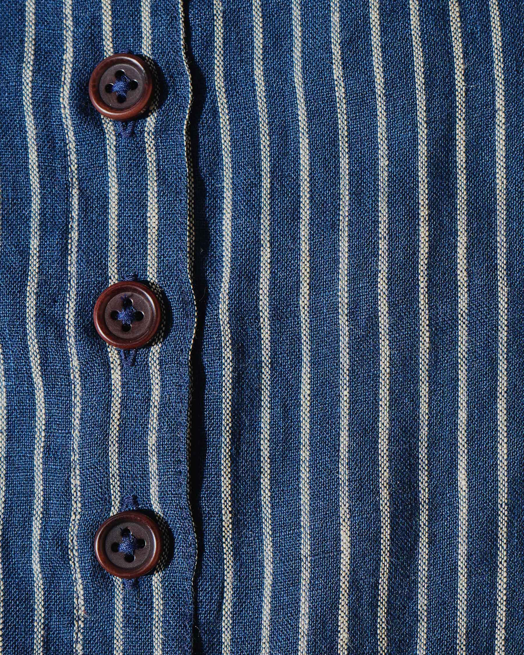 Close-up of Pyne and Smith Clothiers’ No.12 Button Up, Linen Midi Dress in Mariner Stripe, featuring blue and white vertical stripes, four brown buttons on the front, and a shirt-like design.