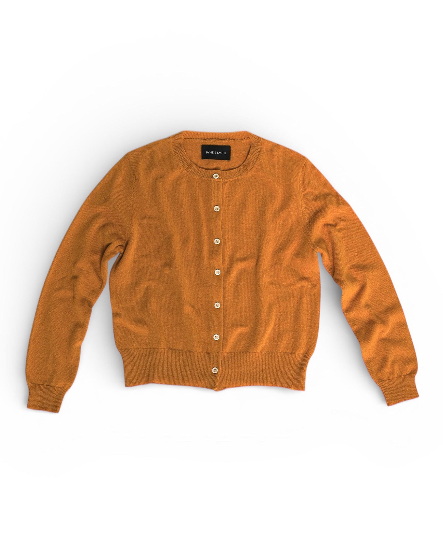 The Pyne and Smith Clothiers Merino Cardigan in Coleman's Yellow is a long-sleeve, mustard-toned wool piece with ribbed cuffs and hem, finished with white front buttons, shown laid flat on a white background.
