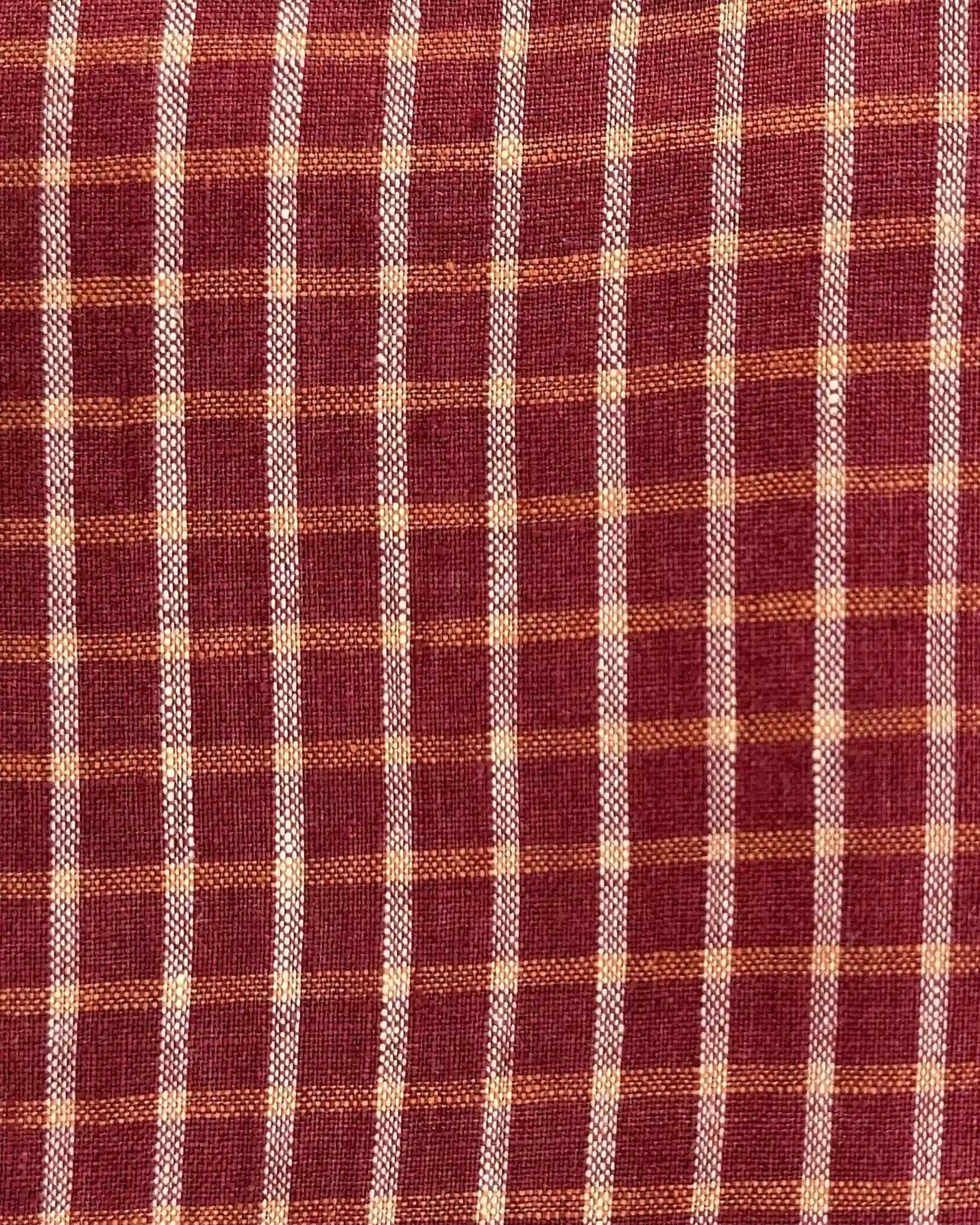 Close-up of the Blouse No.14 Linen T-shirt in Pomodoro Plaid by Pyne and Smith Clothiers, showing its red and orange plaid European linen with a grid of orange, red, and off-white lines. The woven texture is clearly visible.