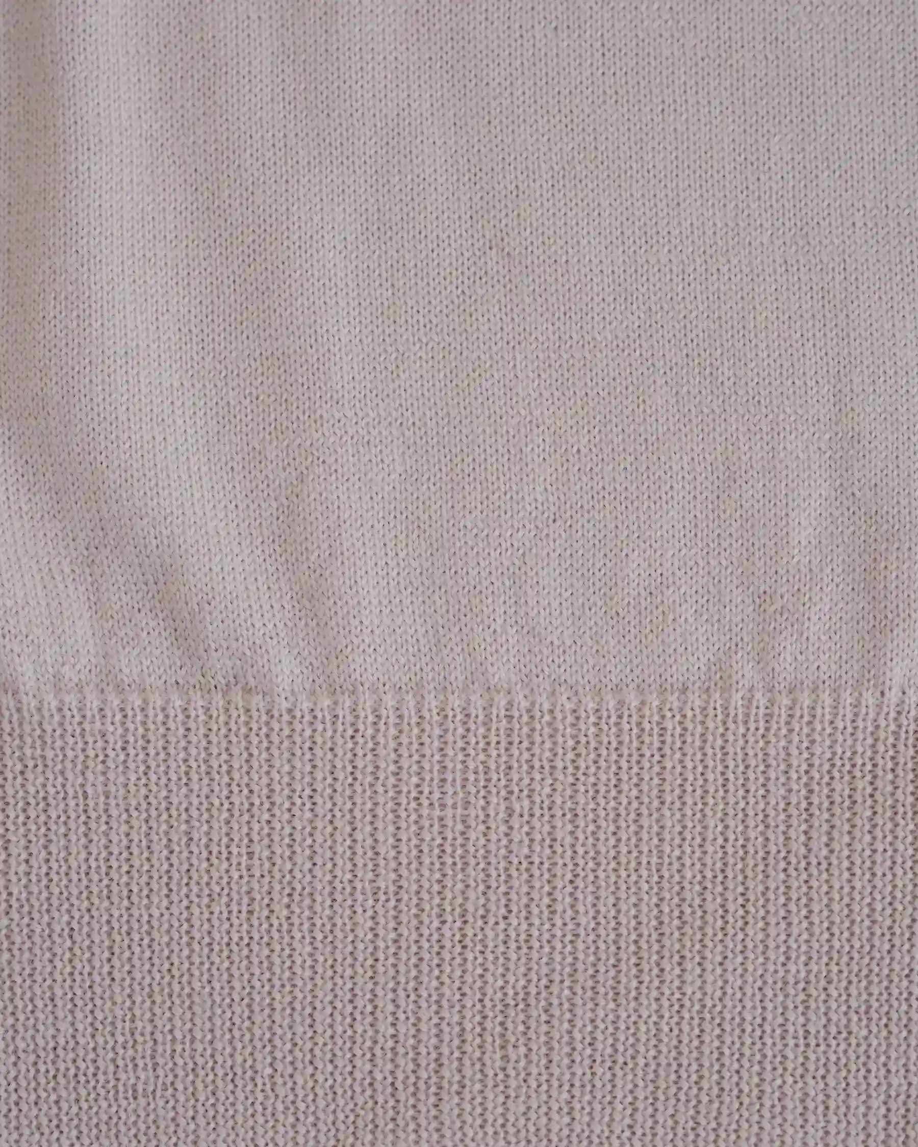 Close-up view of the Merino Polo Shirt in Shell Pink by Pyne and Smith Clothiers, made in Italy from extra fine merino wool, highlighting the ribbed hem and fine knit texture.